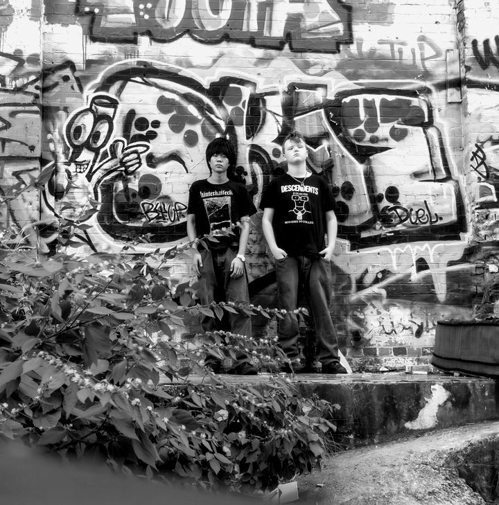 Two kids posed at a spray-painted wall