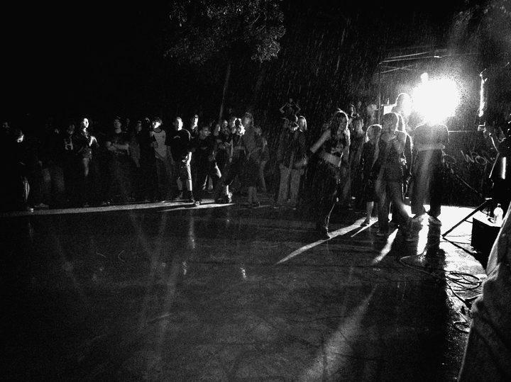 A hundred-plus kids on the wet concrete at Thornlands in the rain, one work light flaring