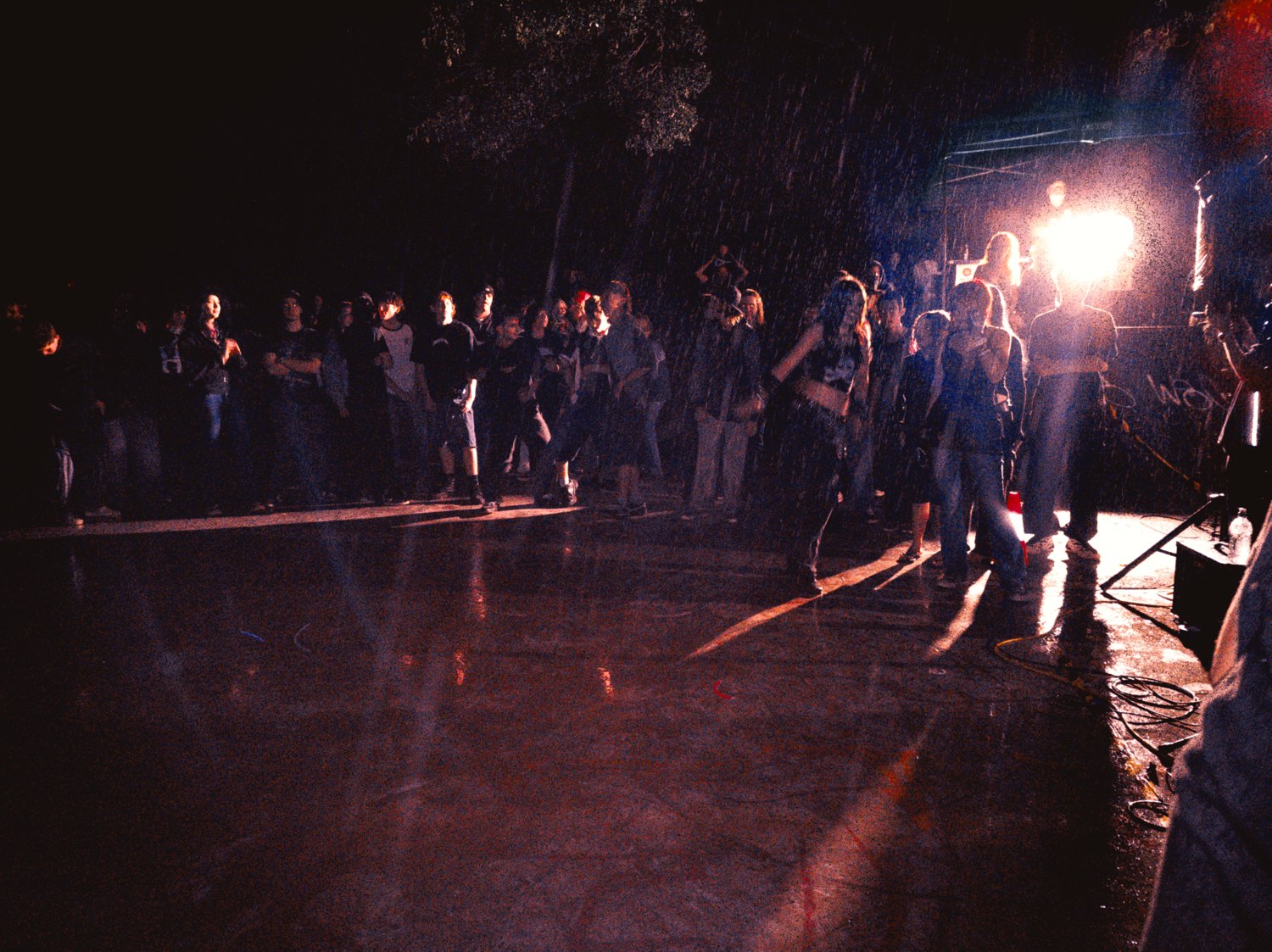 A hundred-plus kids on the wet concrete at Thornlands in the rain, one work light flaring at the side